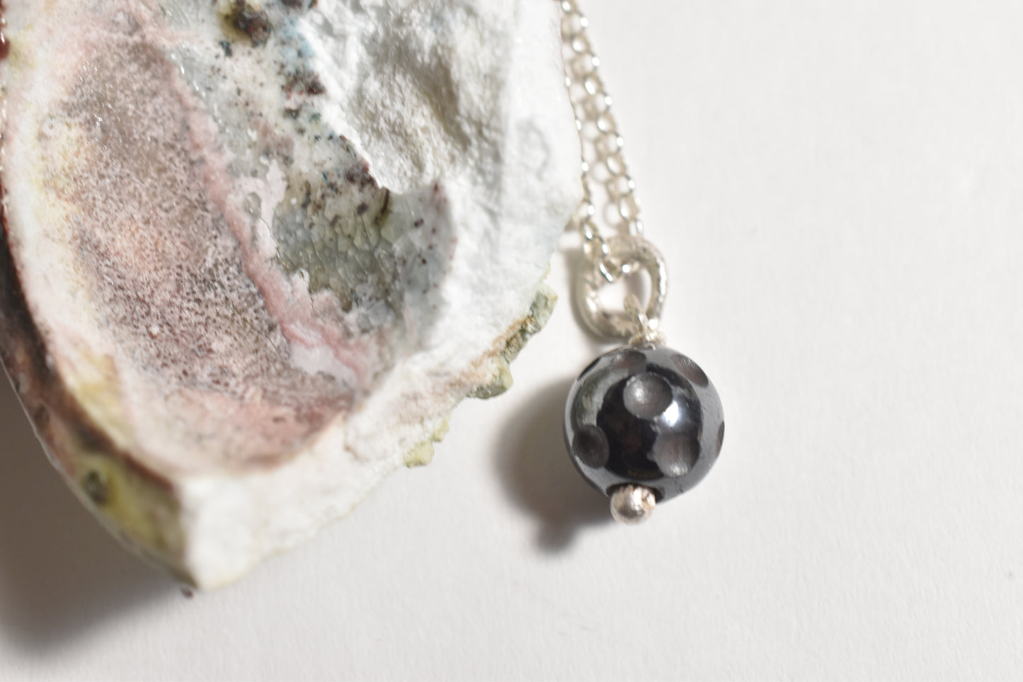 Silver hematite moon crater pendant with carved bead on sterling silver chain