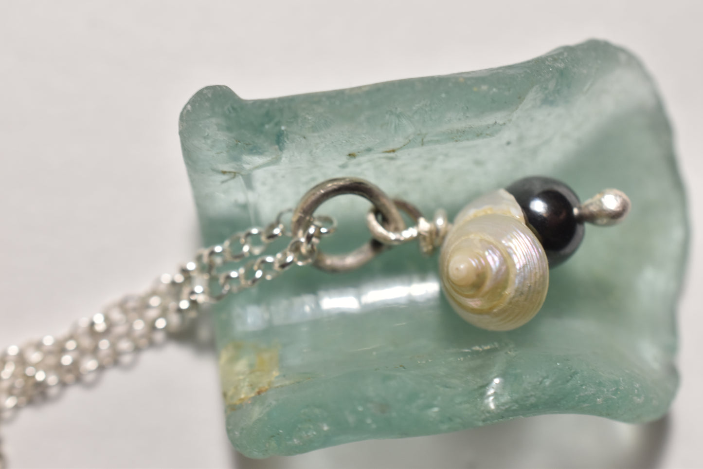Silver seashell and hematite handmade pendant, close-up of delicate shell