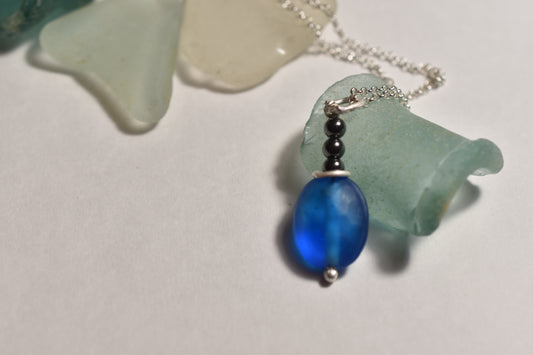 Blue glass and hematite pendant on silver chain, close-up detail view