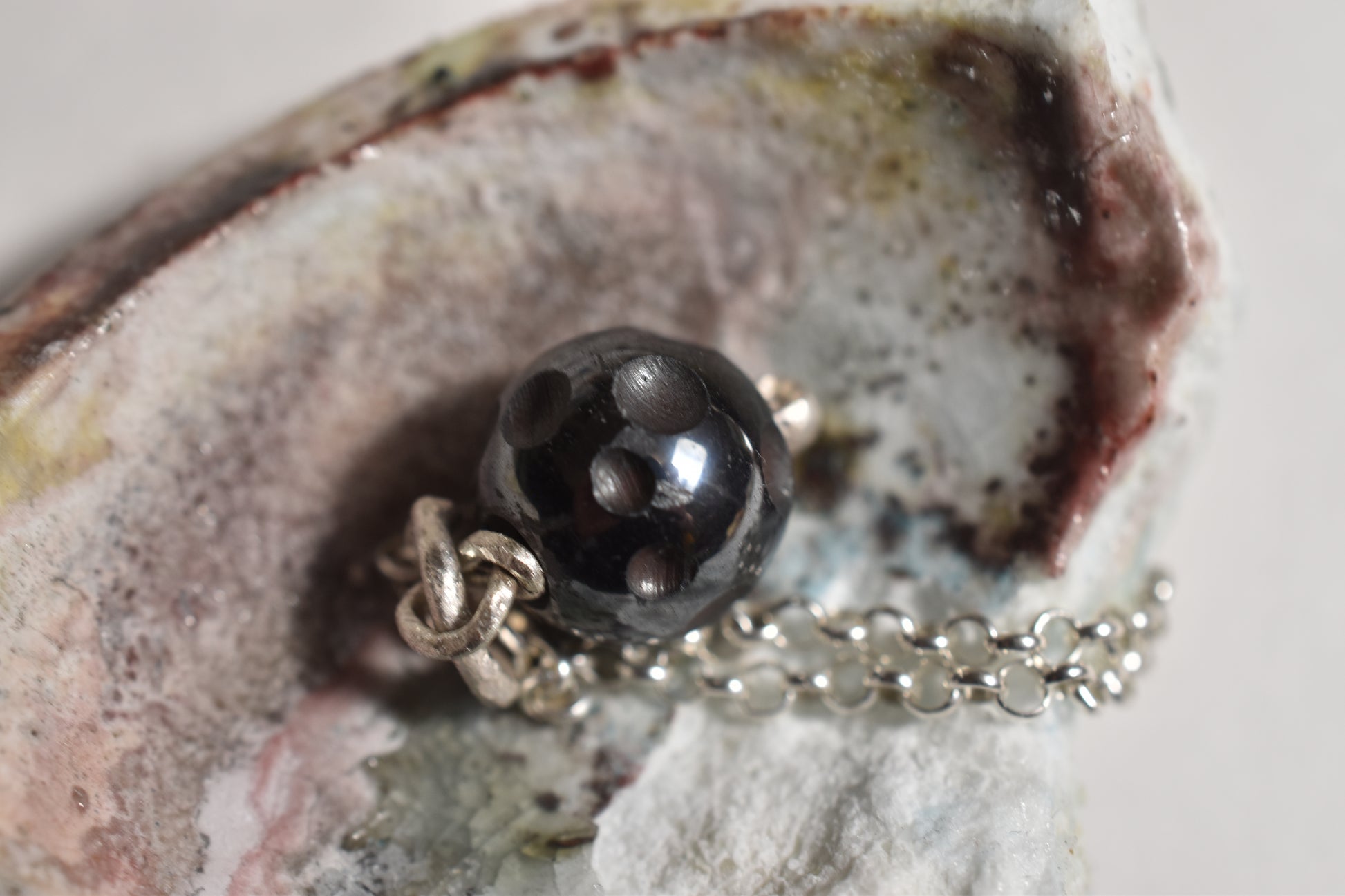 Silver hematite crater pendant close-up, detail of carved moon surface